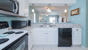 A kitchen with white cabinets, a microwave, a toaster, a stove, a sink, and a dishwasher. - Miramar Beach | Walk to Beach & Shops (Miramar Beach)