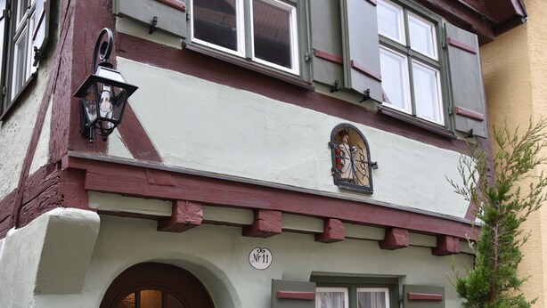 A traditional half-timbered house with a brown door, a small porch, and a potted tree. - The small guest house in the heart of the historic old town of Dinkelsbühl. (Dinkelsbühl)