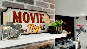 A brick wall with a 'MOVIE Night' sign, a vintage camera, and a plant on a shelf. - Desert Hollywood UofA (Tucson)