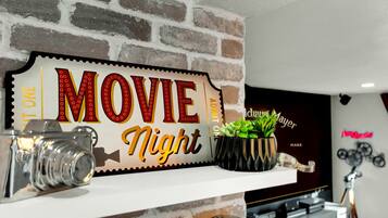 En mur af mursten med et 'MOVIE Night' skilt, et gammelt kamera og en plante på en hylde.