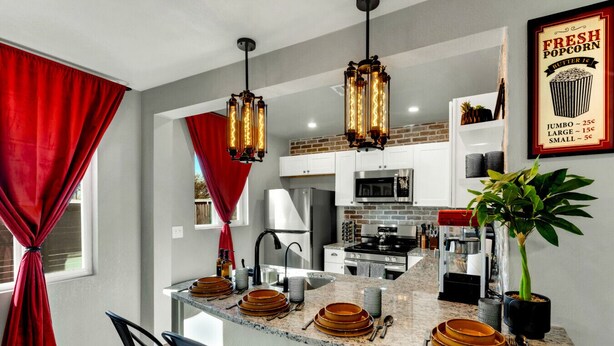 A modern kitchen with a central island, stainless steel appliances, and a red curtain. - Desert Hollywood UofA (Tucson)