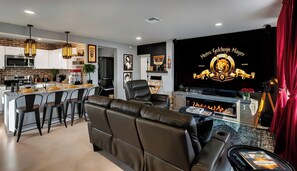 A modern living room with a leather sofa, a TV, and a fireplace. - Desert Hollywood UofA (Tucson)