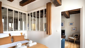 Une chambre d’hôtel avec un grand lit, une télévision, un fauteuil en osier et une vue sur l’extérieur.