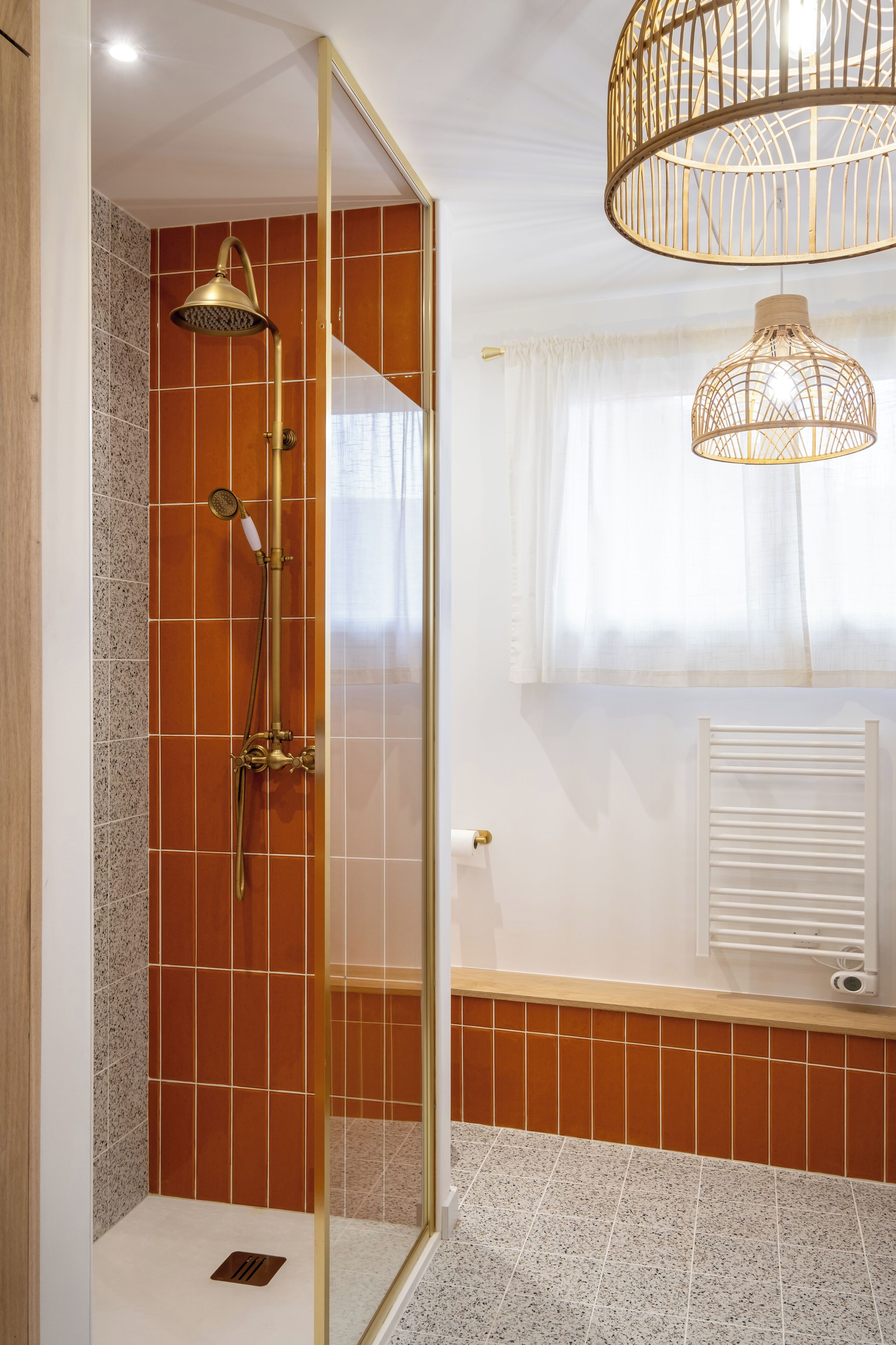 A bathroom with a glass-enclosed shower, a white radiator, and a hanging light fixture.