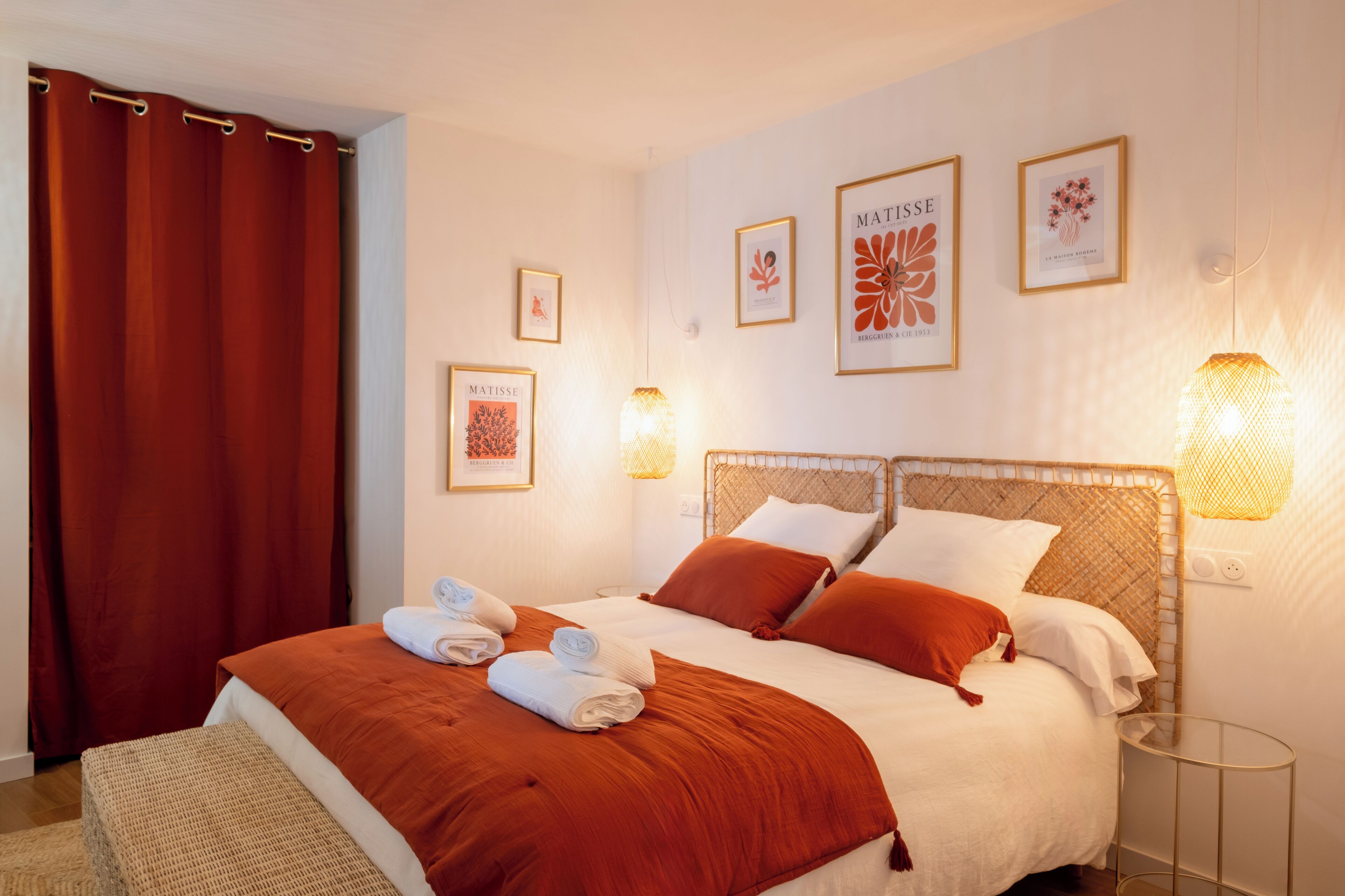 A double bed with two pillows, a bedside table, and wall art.