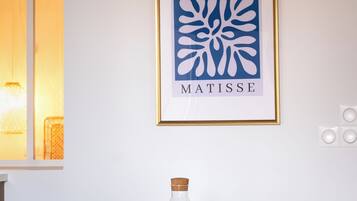 Een eetgedeelte met een ronde tafel voor vier personen, een ingelijste kunstwerk aan de muur en een bijzondere hanglamp erboven.