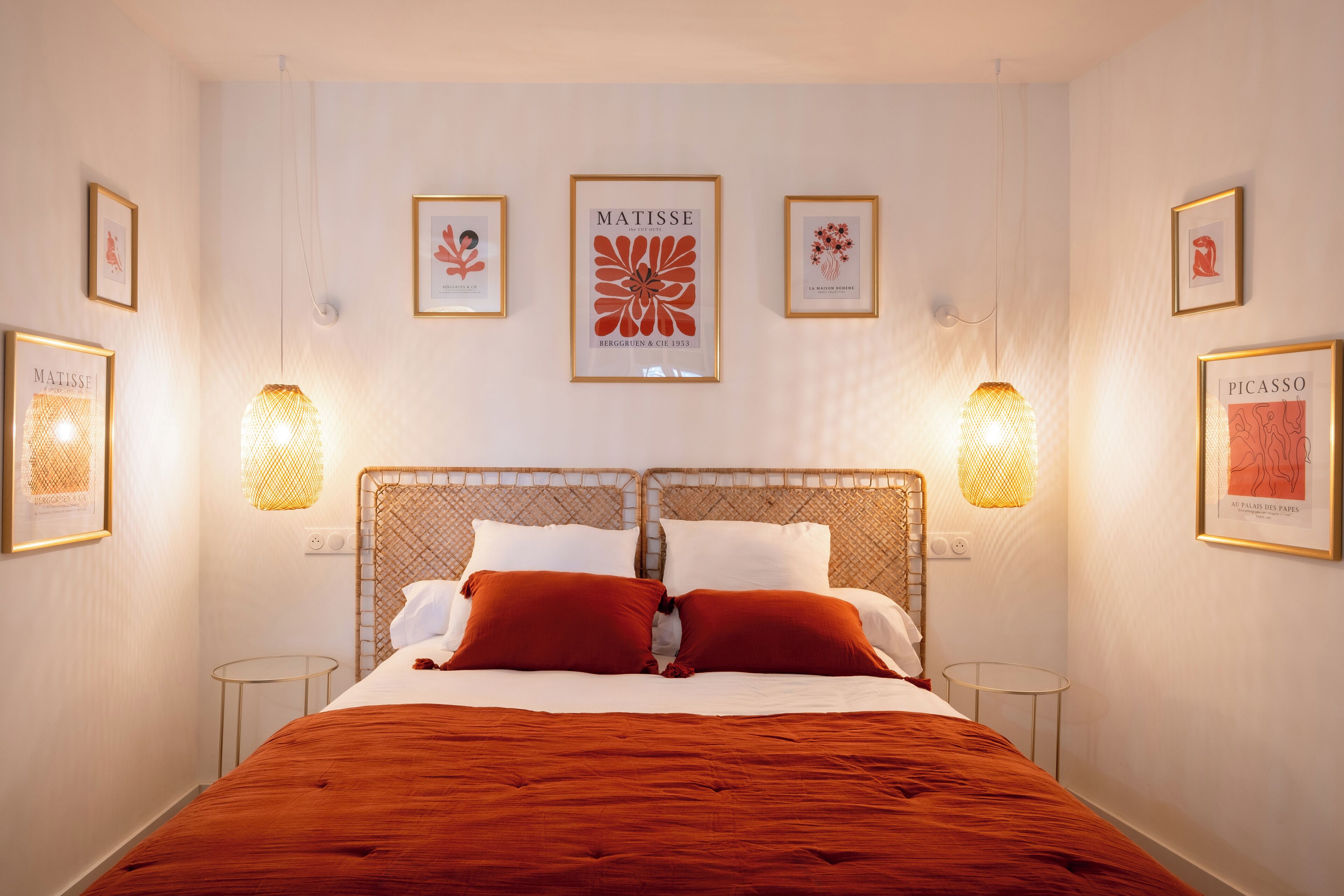 Habitación de hotel ordenada con una cama grande, dos mesitas de noche y cuadros en las paredes.