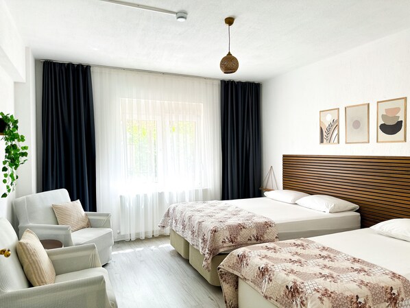 A hotel room with a bed, a chair, a hanging plant, and a window with curtains. - Şahan Apart (Yesilova)