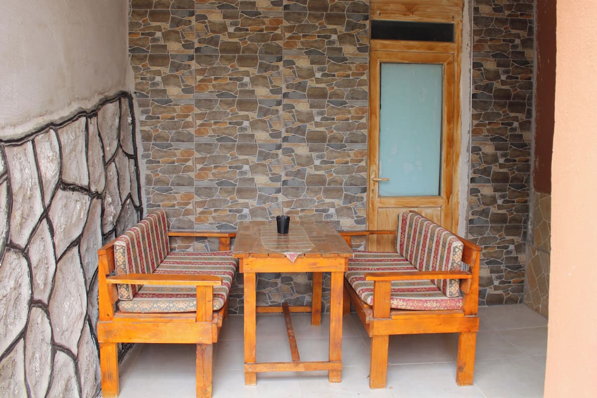 Interior de pared de piedra con una mesa de madera y cuatro sillas.