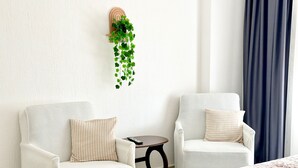 A room with two white armchairs, a small table, and a hanging plant. - Şahan Apart (Yesilova)