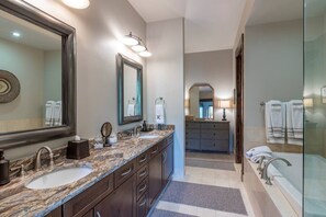 Un baño moderno con dos lavamanos, un espejo grande y un mueble tocador con cajones.