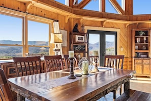 Enjoy meals with family and friends in this spacious dining area with a large table, fireplace, and stunning mountain views.