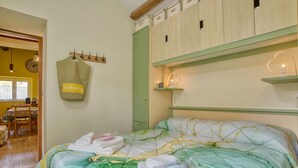 Un dormitorio con una cama, una pared verde, un perchero de madera y un reloj.