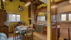 Una cocina acogedora con armarios de madera, una pared de ladrillo y un comedor con una mesa preparada para cuatro.