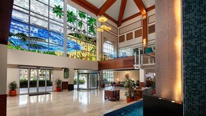 Um hall espaçoso com parede de vidro, piscina e escada que leva a um andar superior.