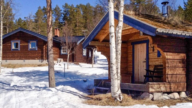 Une cabane en bois avec une véranda, une porte et une fenêtre.