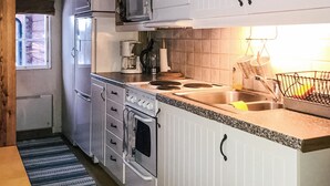 Une cuisine de taille réduite avec des meubles blancs, une cuisinière, un four à micro-ondes et un évier.