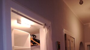 A hallway with a partially open closet door, a light fixture above the door, and a door with a small picture frame on the wall.