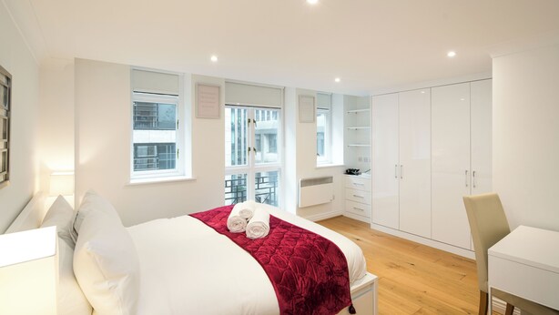A modern bedroom with a large bed, a desk, and a wardrobe. - 1BD Modern City Oasis: Near London Attractions (London)