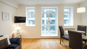 A modern living room with a leather sofa, a glass coffee table, and a dining area with a table and chairs. - 1BD Modern City Oasis: Near London Attractions (London)