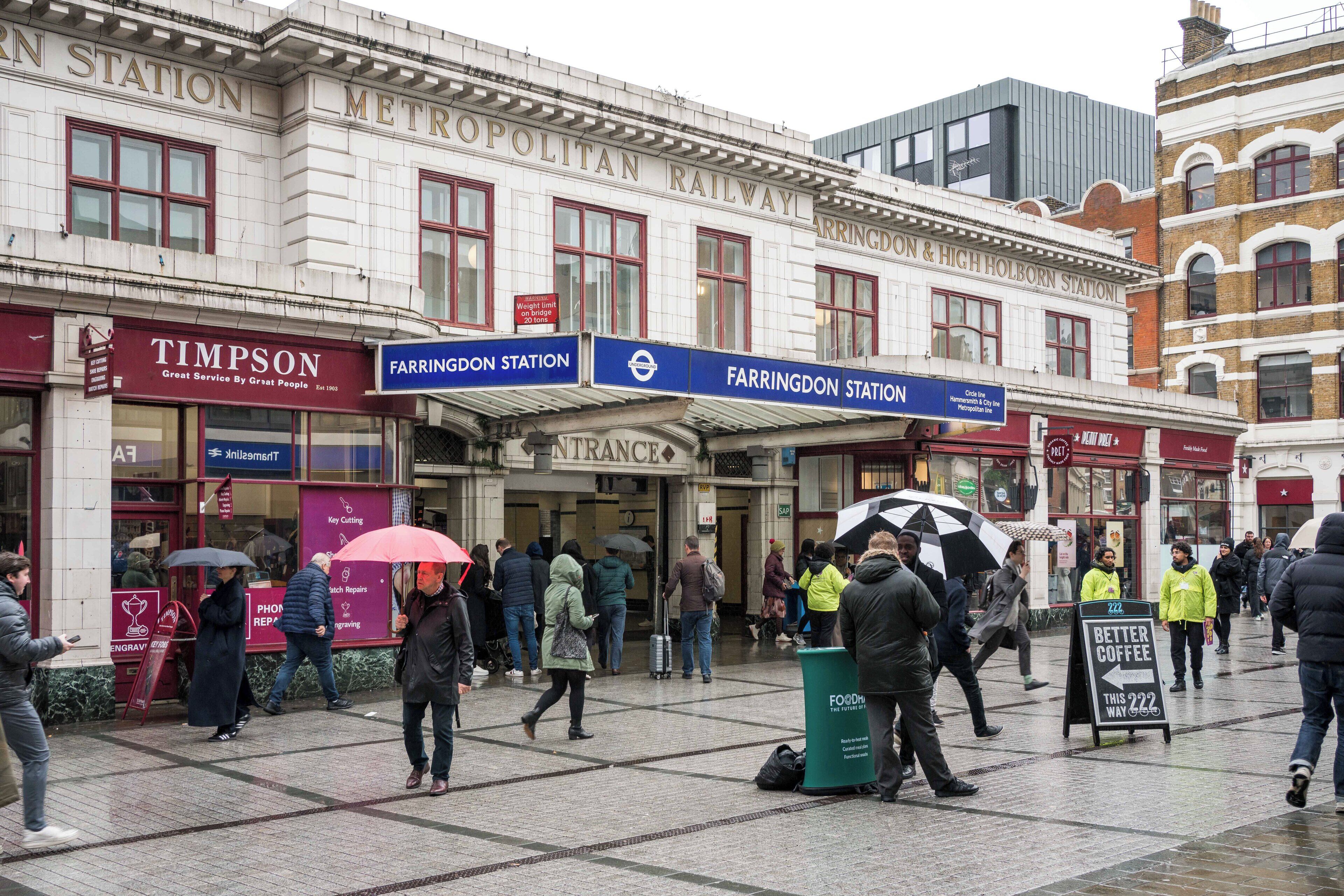 Une place animée en plein cœur de la ville, avec un bâtiment historique portant une enseigne indiquant « Gare de FARRINGDON et de HIGH HOLBORN ».