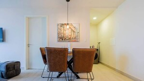 A dining area with a table and four chairs, a painting on the wall, and a door in the background. - Jr. Apartment Upper Level in Casco View (Panamá)