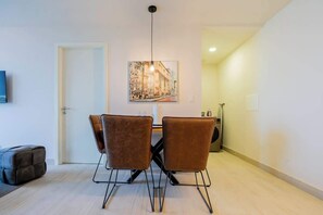 A dining area with a table and four chairs, a painting on the wall, and a door in the background. - Jr. Apartment Upper Level in Casco View (Panamá)