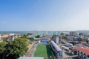 A view of a cityscape with a sports field, buildings, and a clear sky. - Premium Apartment with Bay View (Panamá)