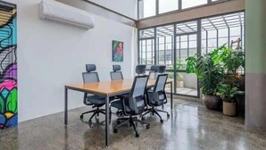 Un salón de conferencias con una gran mesa, sillas y vistas amplias a través de grandes ventanales.