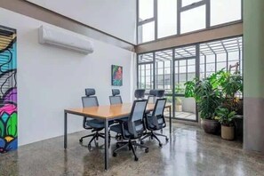 A conference room with a large table, chairs, and a view through large windows.