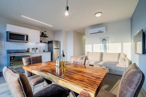 Una cocina moderna con armarios blancos, una mesa de comedor de madera y un horno empotrado.