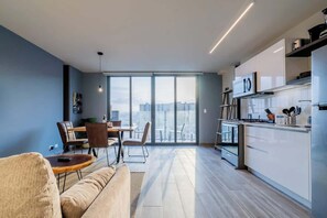 A modern apartment with a kitchen, dining area, and a large window offering a city view. - Upper Apartment with Ancon Hill & City Views (Panamá)