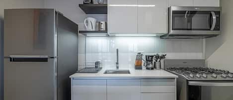 A modern kitchen with stainless steel appliances, white cabinetry, and a built-in microwave.