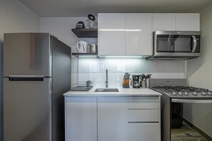 A modern kitchen with stainless steel appliances, white cabinetry, and a built-in microwave.