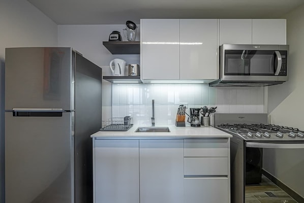 A modern kitchen with stainless steel appliances, white cabinetry, and a built-in microwave.