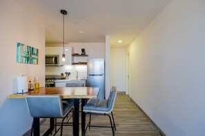 Een moderne keuken met een eethoek, met een houten tafel, twee stoelen en een hanglamp.
