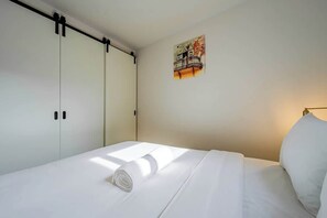 Una habitación de hotel con una cama, un cuadro en la pared y un armario.