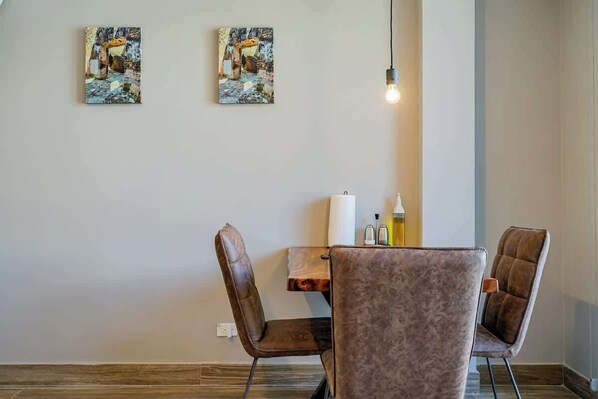 Un área de comedor con una mesa y sillas, dos obras de arte en la pared y una lámpara colgante.