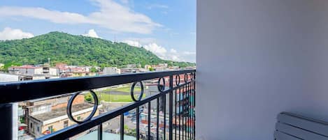 A balcony with a view of a cityscape and a hill.