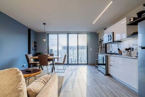 A modern apartment with a dining area, kitchen, and large windows offering a city view. - Apartment Upper Level in Casco View (Panamá)