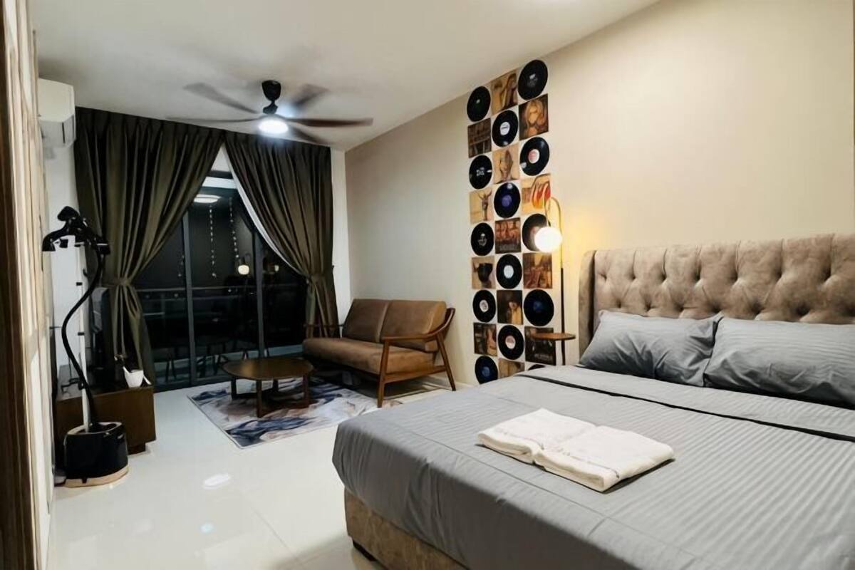A bedroom with a bed, a ceiling fan, a wall-mounted light, a sofa, and a view of the outside.