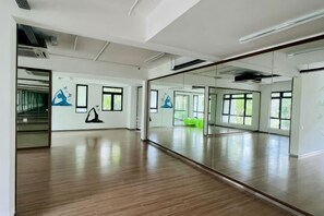 Una habitación amplia con un espejo grande, suelo de madera y ventanas que dejan entrar luz natural.