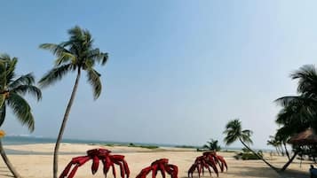 Una playa con palmeras y esculturas de cangrejos rojos.