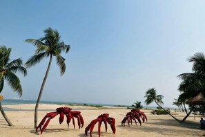 A beach with palm trees and red crab sculptures. - Gelang Patah Forest City-Ataraxia Park 3 (Gelang Patah)