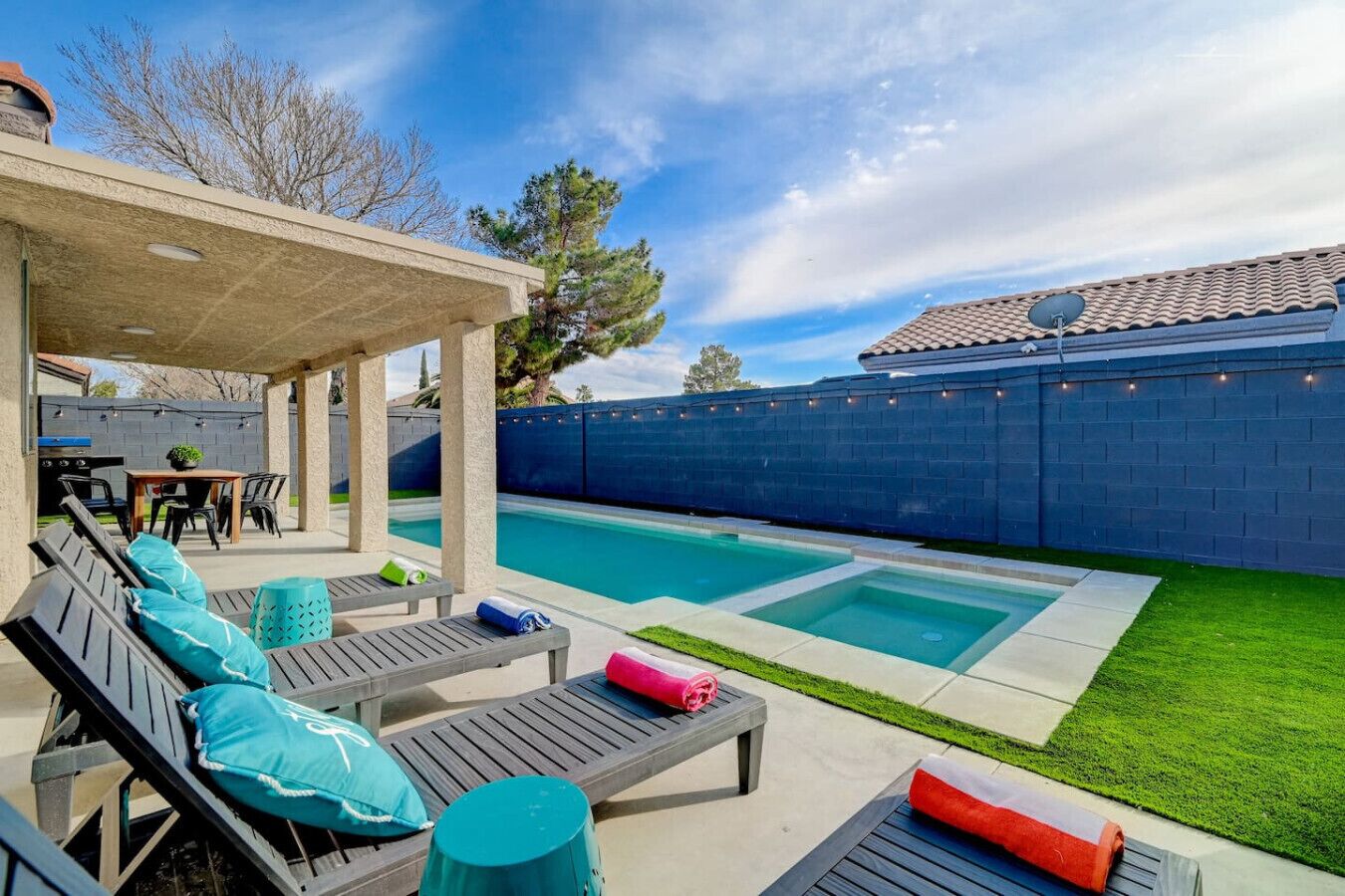 A backyard with a pool, outdoor seating, and a covered patio area.