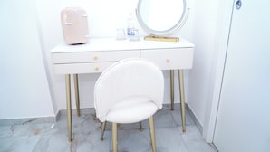 A white vanity with a round mirror, a beige appliance, and a chair. - Lifestyle Naples B&B (Naples)