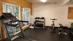 Un gimnasio con cinta de correr, mancuernas y máquinas de pesas.