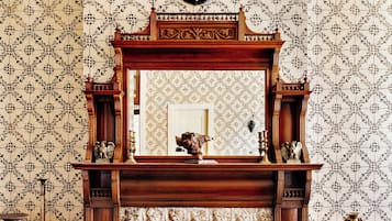 A room with a fireplace, a mirror, and patterned wallpaper.