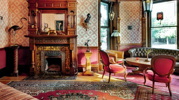 Une pièce de style traditionnel, dotée d’une cheminée, de meubles richement décorés et d’un papier peint à motifs.