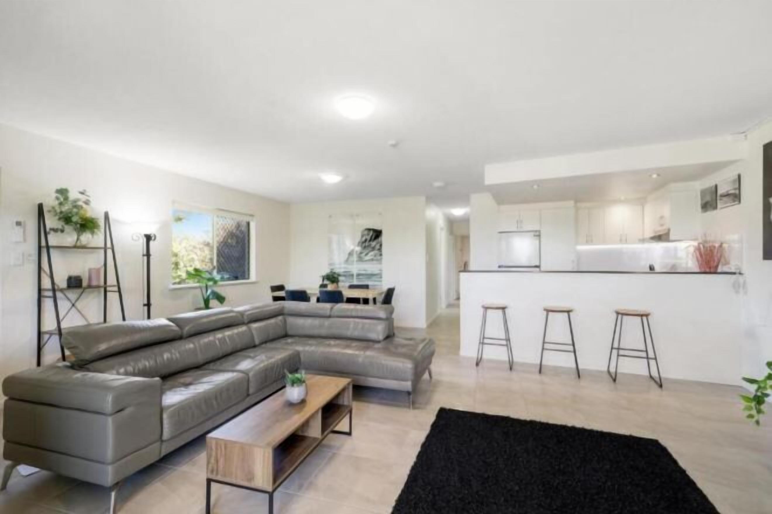 Una sala moderna con un sofá modular, una mesita de madera y una alfombra negra.
